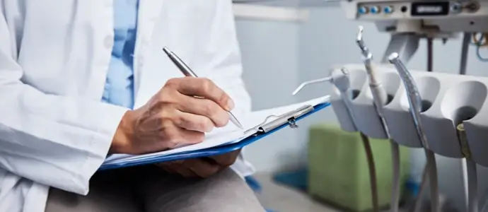 Shot of an unrecognisable dentist writing notes on a piece of paper