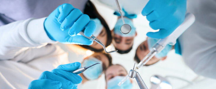 Five dentists with special tools in their hands, people in medical uniforms and protective gloves